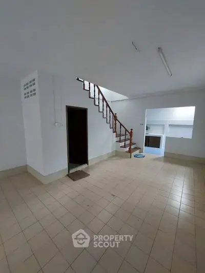 Spacious interior with tiled floor and wooden staircase, ideal for modern living.