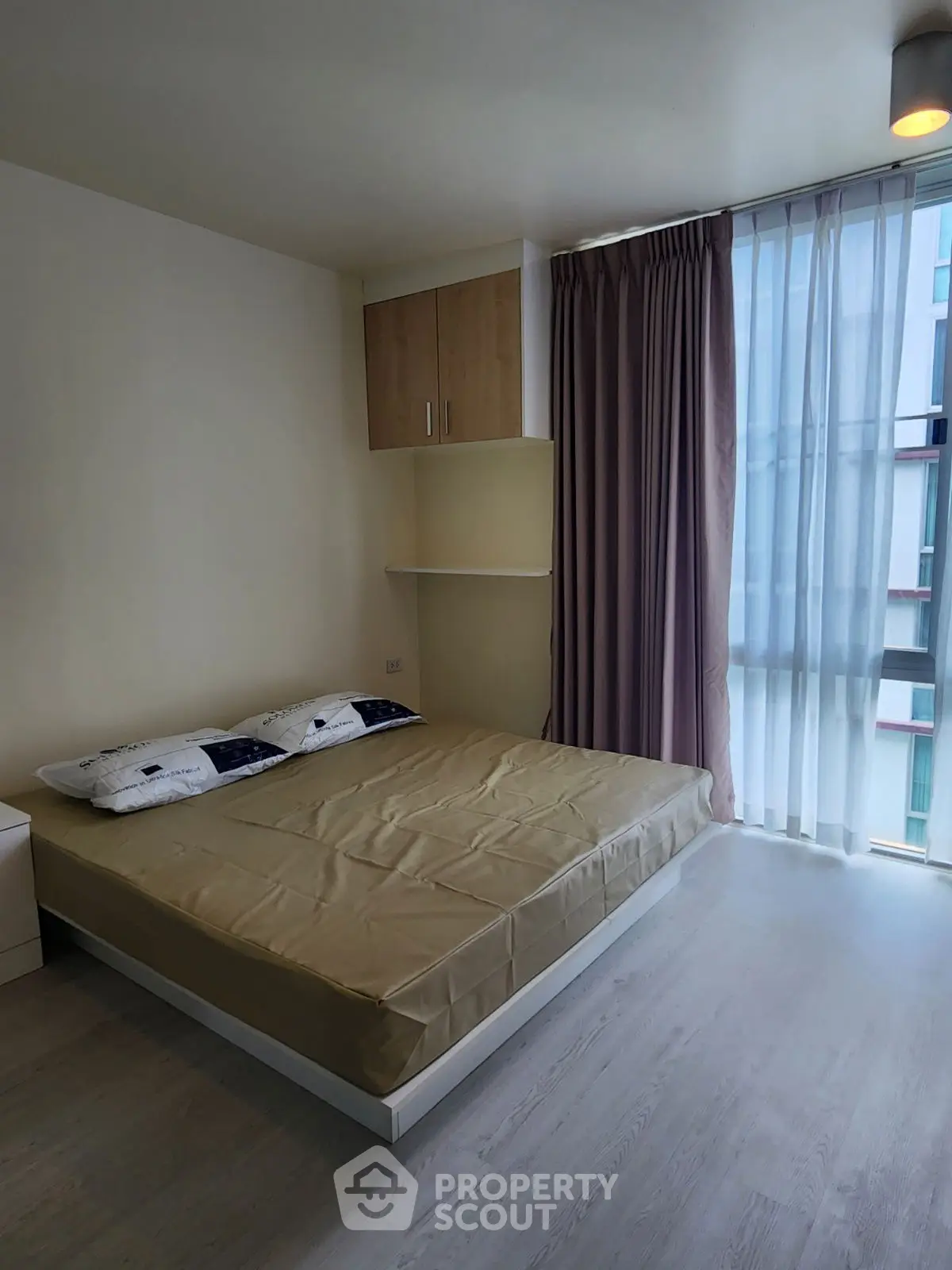 Modern bedroom with large window and minimalist decor in urban apartment.