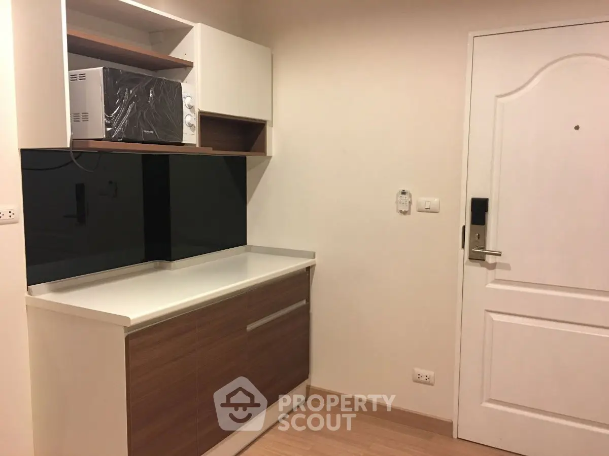 Compact kitchen area with modern cabinetry and microwave, ideal for small apartments.