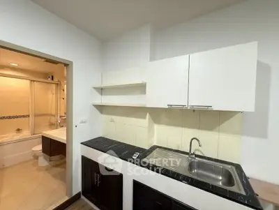 Modern kitchen with sleek cabinetry and adjacent bathroom featuring a bathtub, perfect for compact living spaces.
