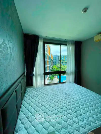 Modern bedroom with large window offering a stunning view of the pool and surrounding buildings.