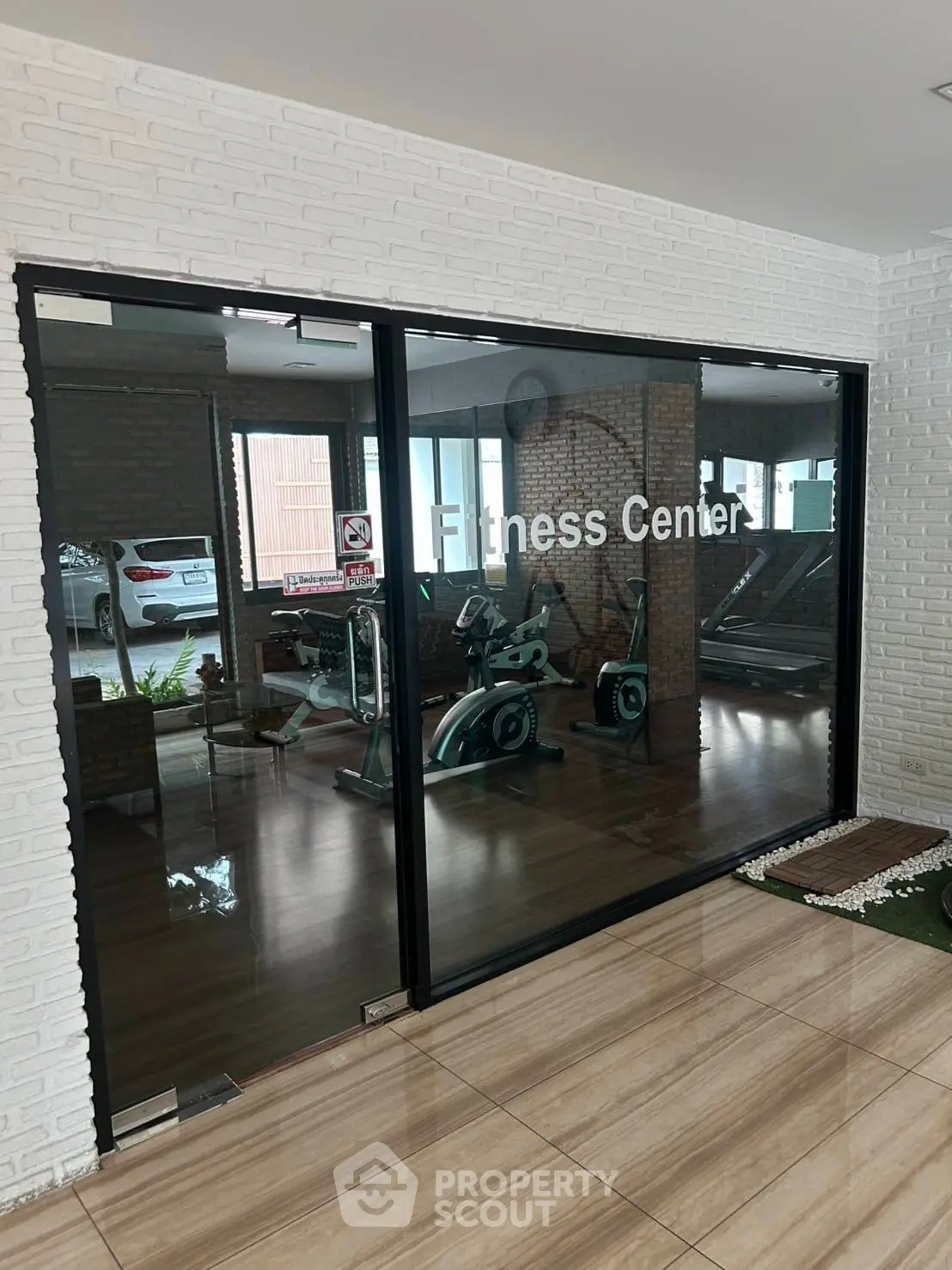 Modern fitness center with glass walls and exercise equipment in a residential building.