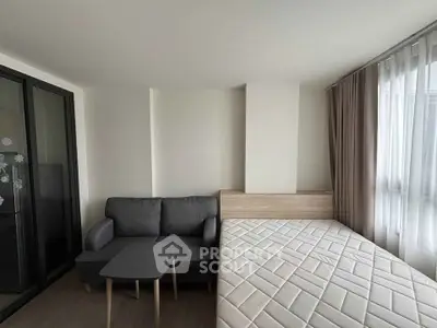 Modern studio apartment with cozy sofa and bed near large window.