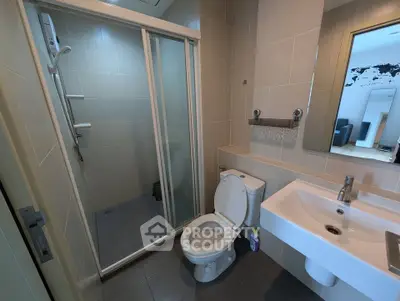 Modern bathroom with glass shower and sleek fixtures in contemporary apartment.