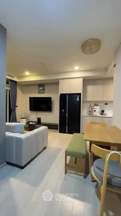 Modern living room with open kitchen, featuring sleek furniture and contemporary design.