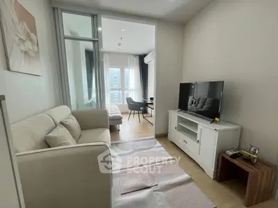 Modern living room with cozy sofa and TV, bright natural light from large window.