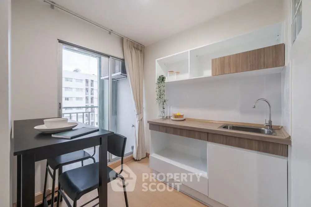 Modern compact kitchen with sleek design and balcony view, perfect for urban living.