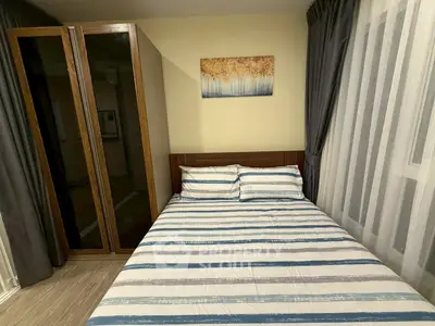 Cozy bedroom with striped bedding and elegant wardrobe, perfect for a restful retreat.
