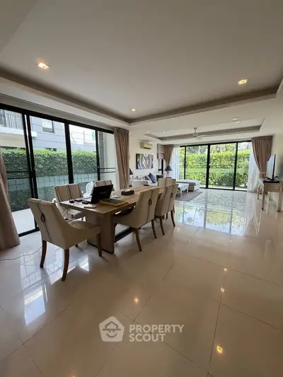 Spacious open-plan living and dining area with large windows and garden view.