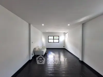 Spacious minimalist living room with sleek black flooring and ample natural light.
