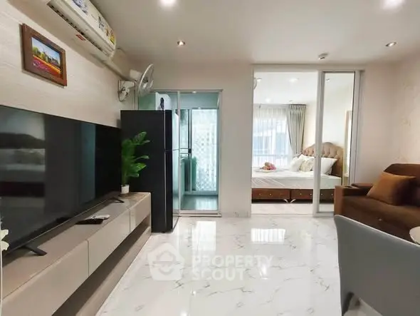Modern living room with sleek TV unit and view into cozy bedroom