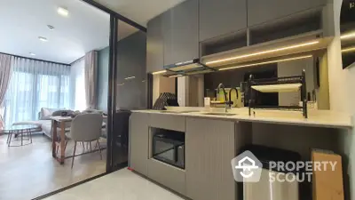 Modern kitchen with sleek gray cabinetry and built-in appliances seamlessly opens to a cozy living area, perfect for entertaining and relaxation.