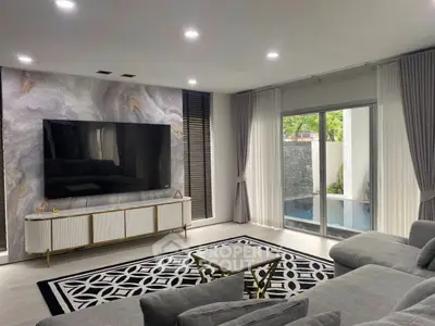 Luxurious living room with modern decor, large TV, and pool view through sliding glass doors.