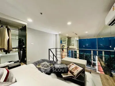 Modern loft bedroom with stylish decor and open closet, featuring a cozy ambiance and city view.