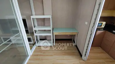 Compact study area with glass desk and shelving, adjacent to modern kitchen.