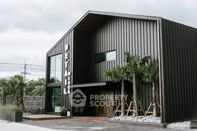 Modern industrial-style building with sleek black exterior and palm trees.