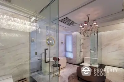 Luxurious bathroom with marble tiles, elegant glass shower enclosure, and sophisticated chandelier lighting, offering a spa-like retreat in a high-end home.