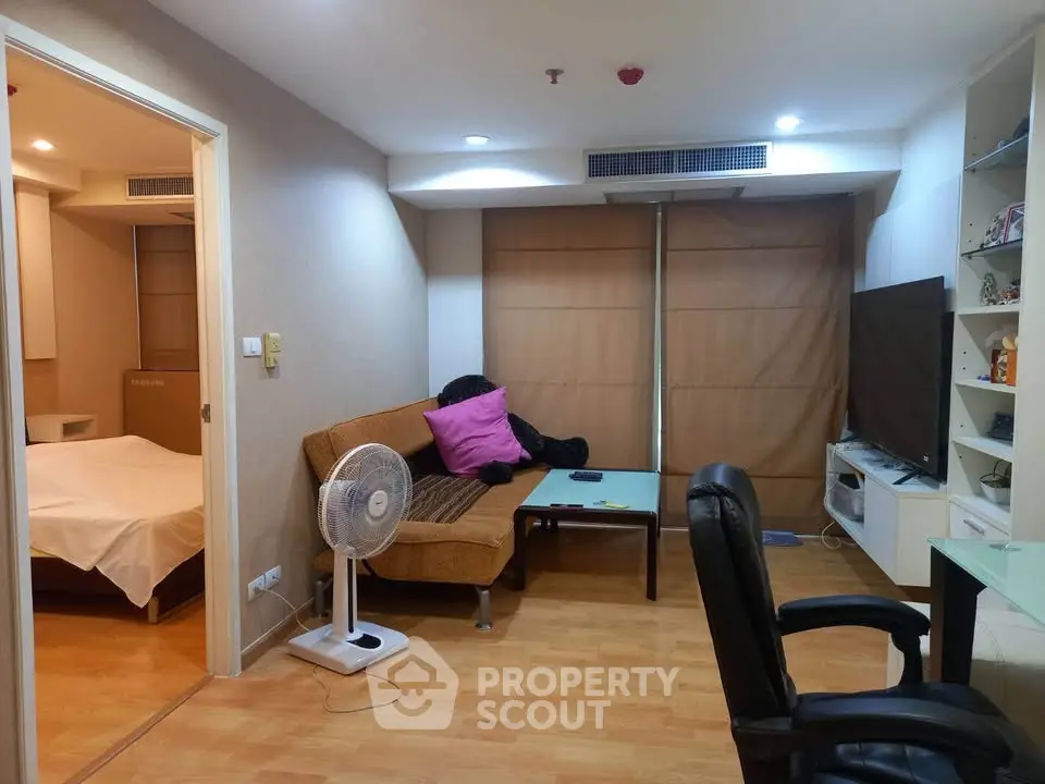 Cozy living room with modern decor and adjacent bedroom in urban apartment.