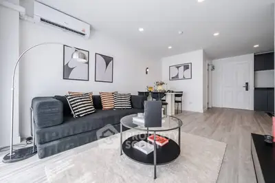 Modern living room with stylish decor, featuring a sleek black sofa, elegant lighting, and contemporary artwork.