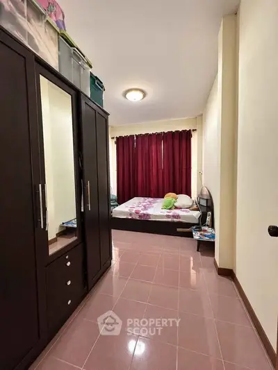 Cozy bedroom with wardrobe and bed, featuring warm lighting and red curtains.