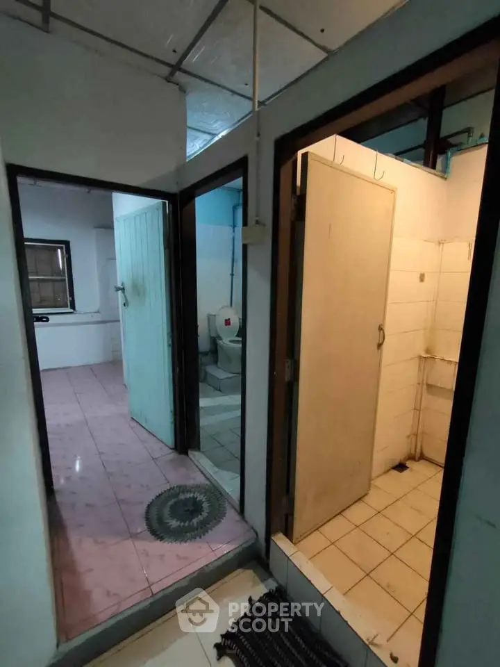 Compact bathroom with adjacent toilet and shower area in modest home setting.