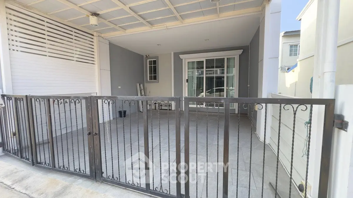 Modern townhouse entrance with gated parking area and sleek design.