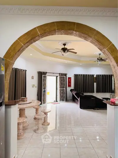 Spacious living room with elegant archway and modern ceiling fans