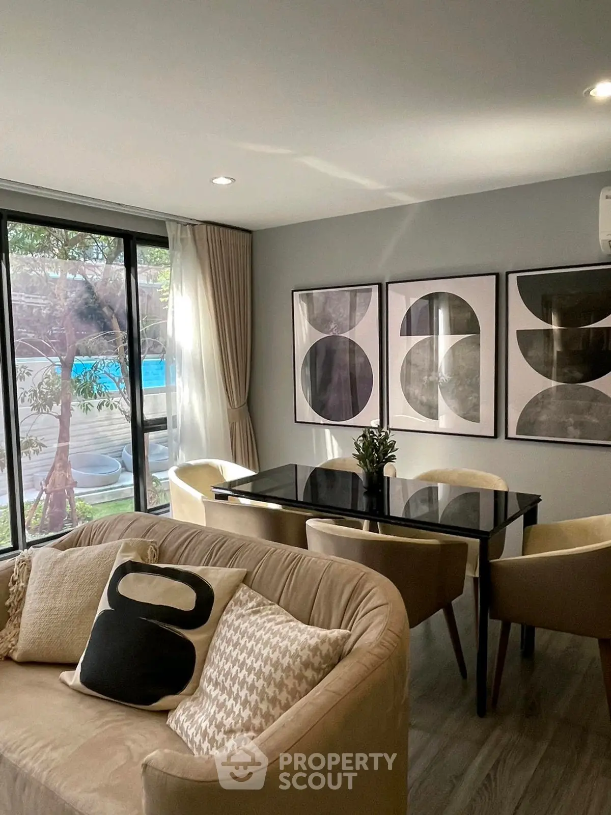 Stylish living room with modern decor and pool view, featuring elegant furniture and abstract art.