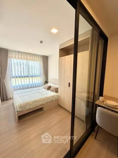 Modern bedroom with sliding glass door and natural light, featuring cozy bed and stylish decor.