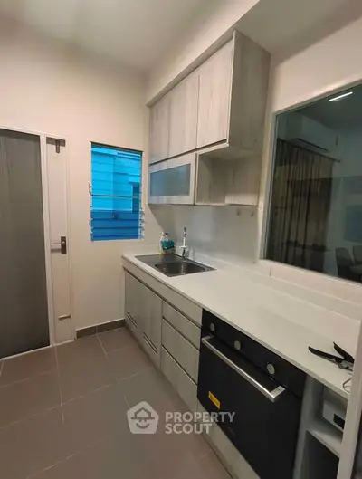 Modern kitchen with sleek cabinetry and built-in oven in a compact layout.