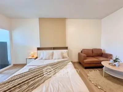 Spacious bedroom with cozy seating area and modern decor