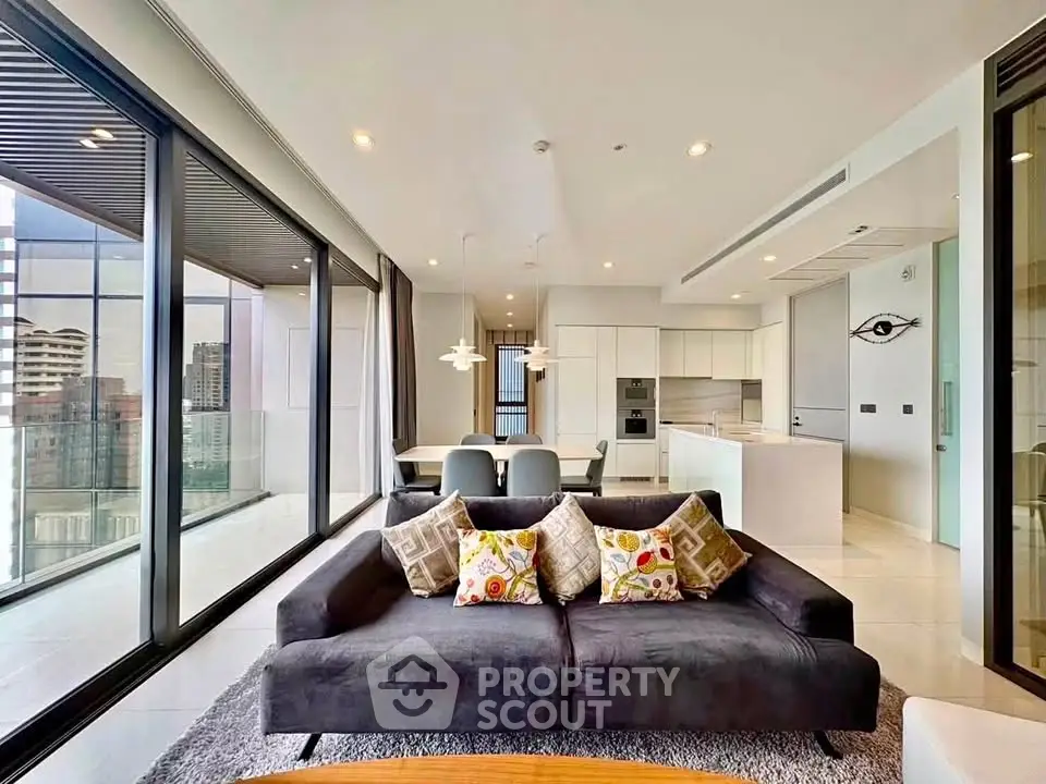 Luxurious modern living room with panoramic city views and sleek open kitchen design.