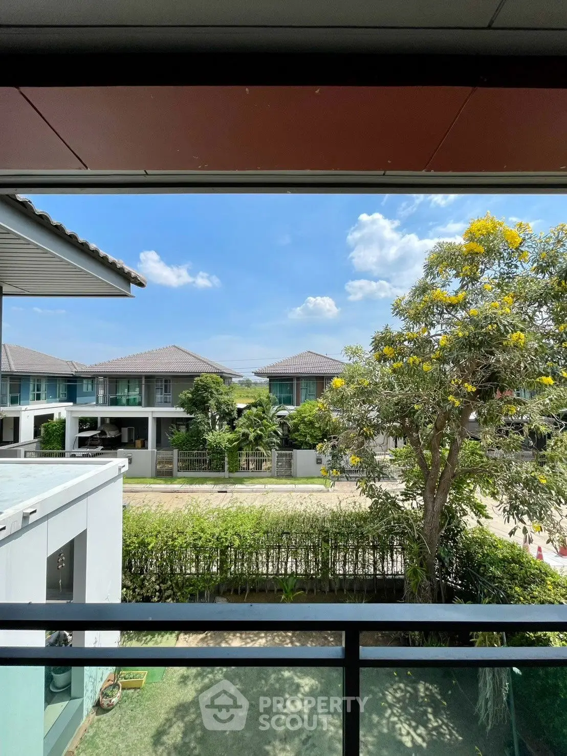 Scenic view from balcony overlooking modern suburban homes and lush greenery.