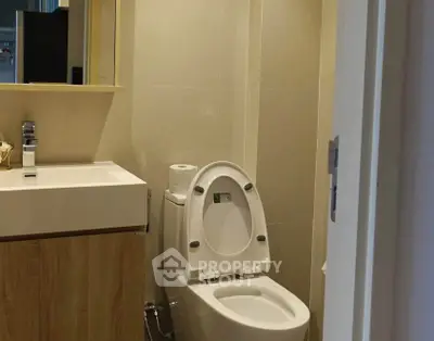 Modern bathroom with sleek fixtures and neutral tones, featuring a stylish vanity and toilet.