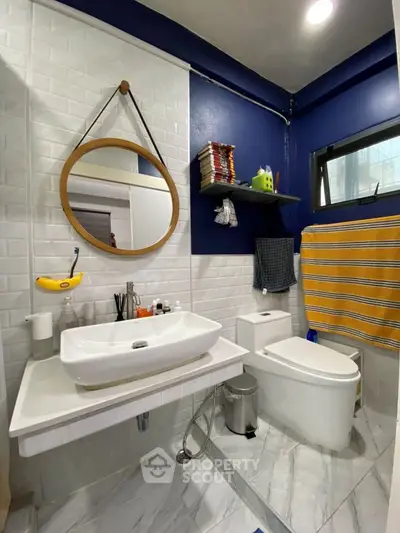 Modern bathroom with stylish round mirror and blue accent wall
