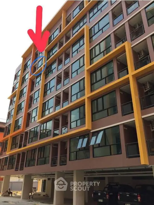 Modern apartment building with unique yellow accents and covered parking area.