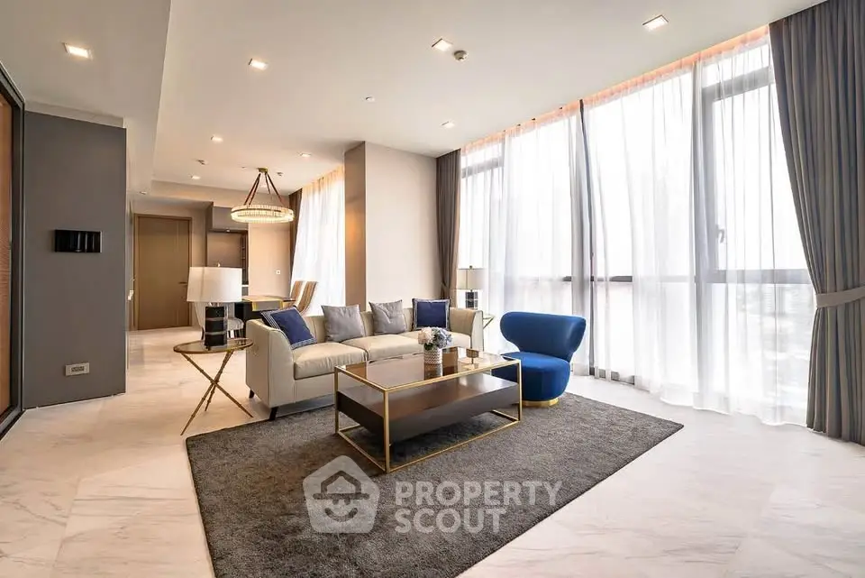 Luxurious modern living room with elegant furniture and large windows offering abundant natural light.