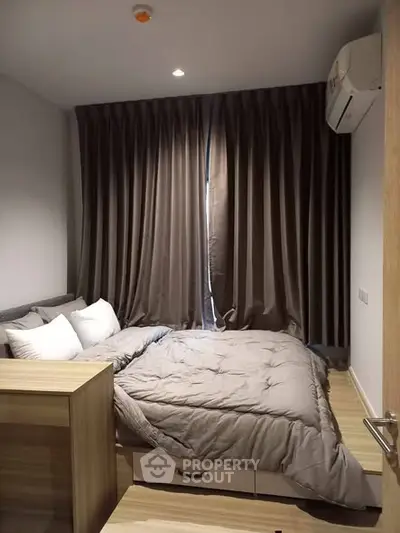 Cozy modern bedroom with elegant curtains and air conditioning, perfect for restful nights.