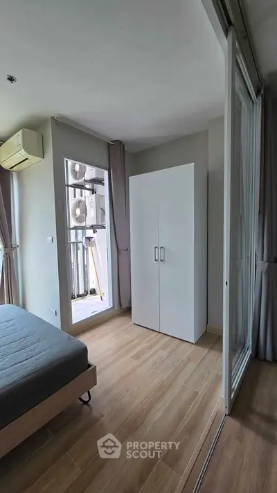 Modern bedroom with wooden flooring, large wardrobe, and balcony access in a stylish apartment.