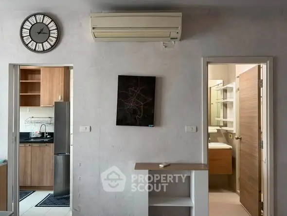 Modern apartment interior with kitchen and bathroom view, featuring air conditioning and stylish wall clock.