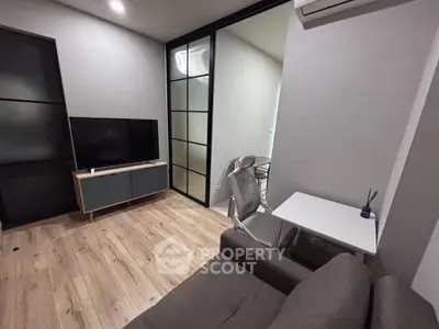 Modern living room with sleek design, featuring a TV, stylish furniture, and elegant glass partition.