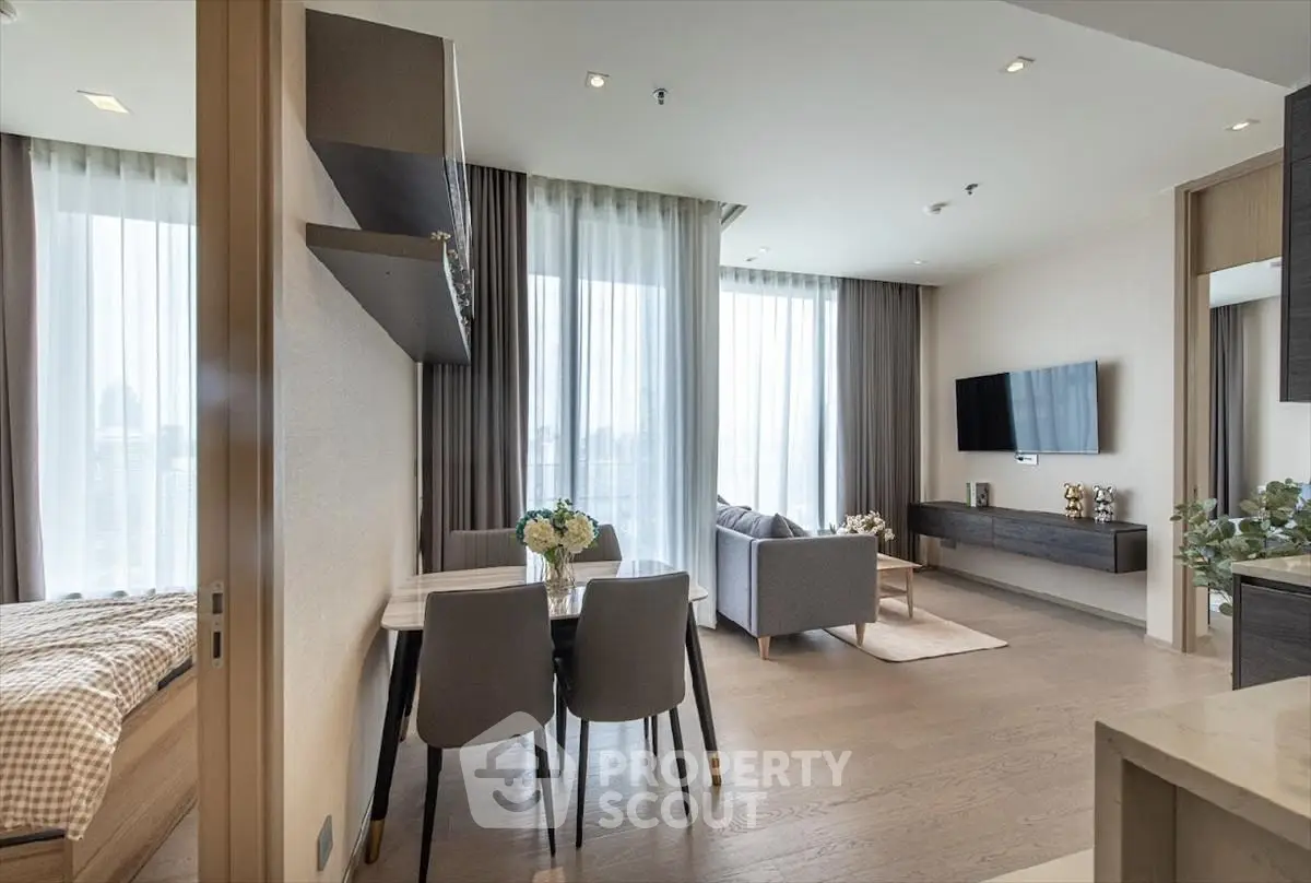Modern open-plan living room with dining area and large windows in a stylish apartment.