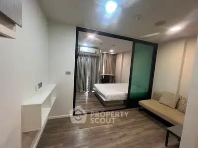 Modern apartment with glass partition separating bedroom and living area, featuring sleek design and cozy ambiance.