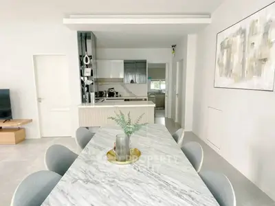 Modern dining area with marble table and sleek kitchen in open layout design.