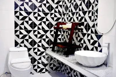 Modern bathroom with geometric black and white tiles and stylish fixtures.