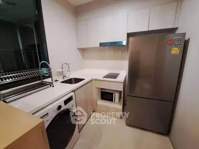 Modern kitchen with sleek appliances and integrated washing machine in compact layout.