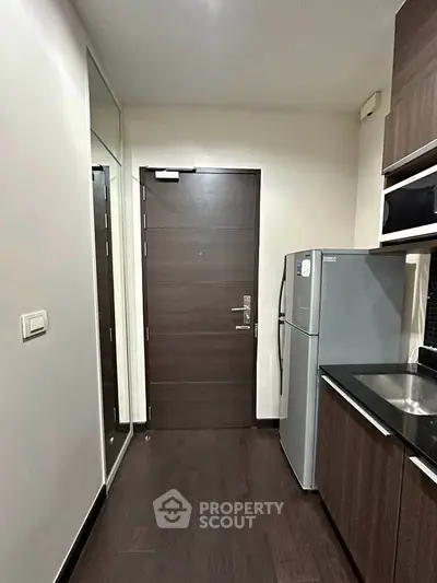 Modern kitchen with sleek cabinetry and stainless steel fridge in a compact layout.