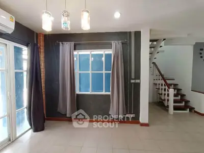 Spacious living room with modern lighting and staircase in a stylish home.