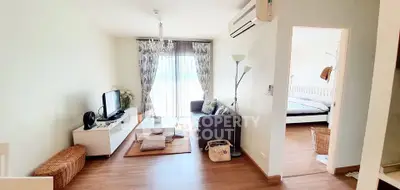 Charming living room with cozy decor and natural light, adjacent to a stylish bedroom.