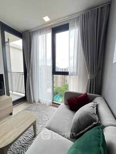 Modern living room with large windows and balcony access, featuring stylish furniture and a cozy atmosphere.